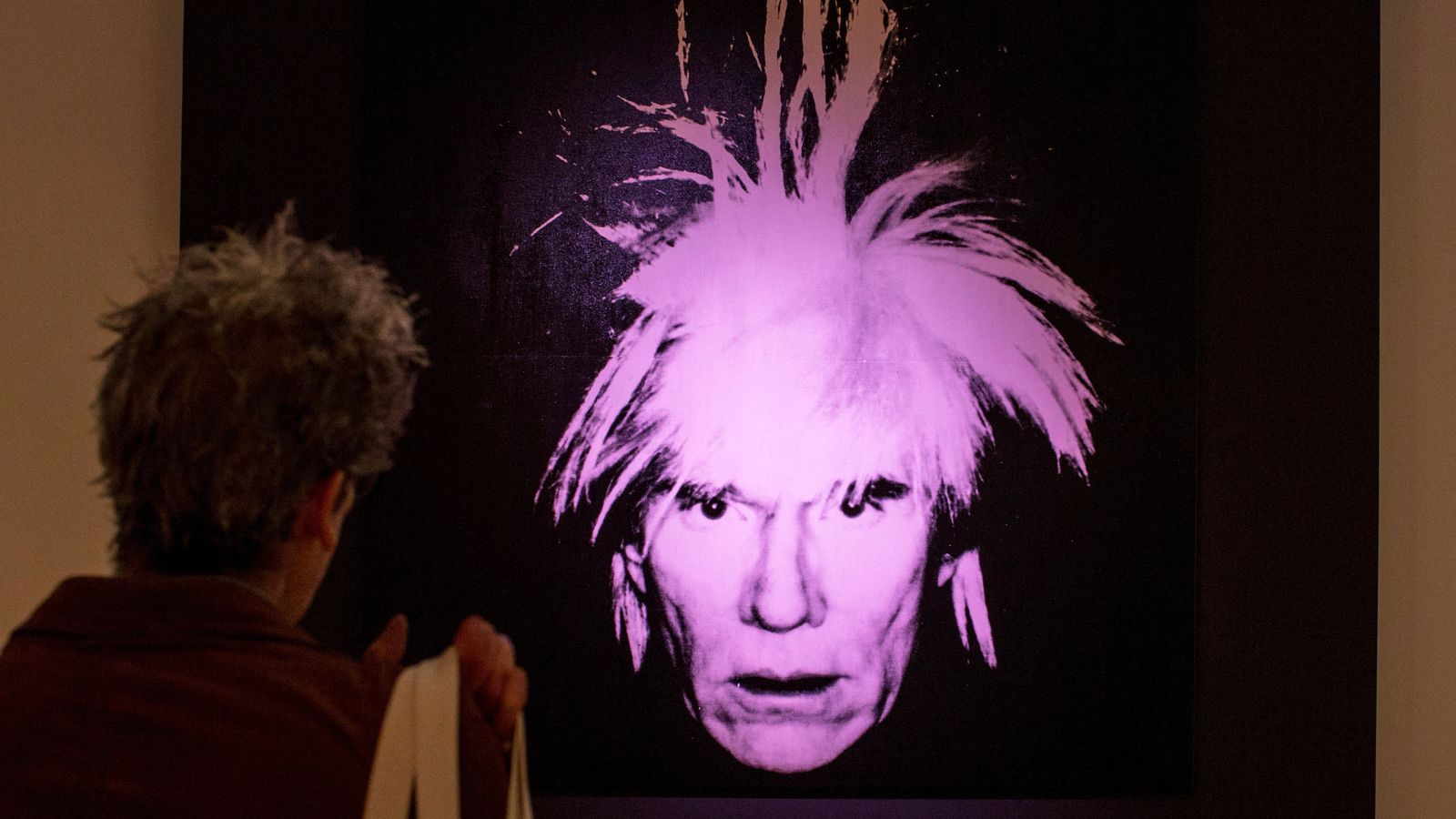 Un home mira l'autoretrat d'Andy Warhol en una subhasta