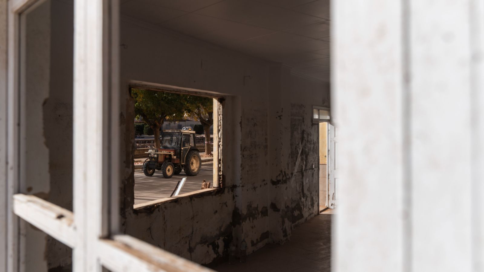 Tractor pel barri de la Fuente d'Utiel, vist des del HUECO d'una finestra d'una vivenda del barri de la Fuente assolada per la dana