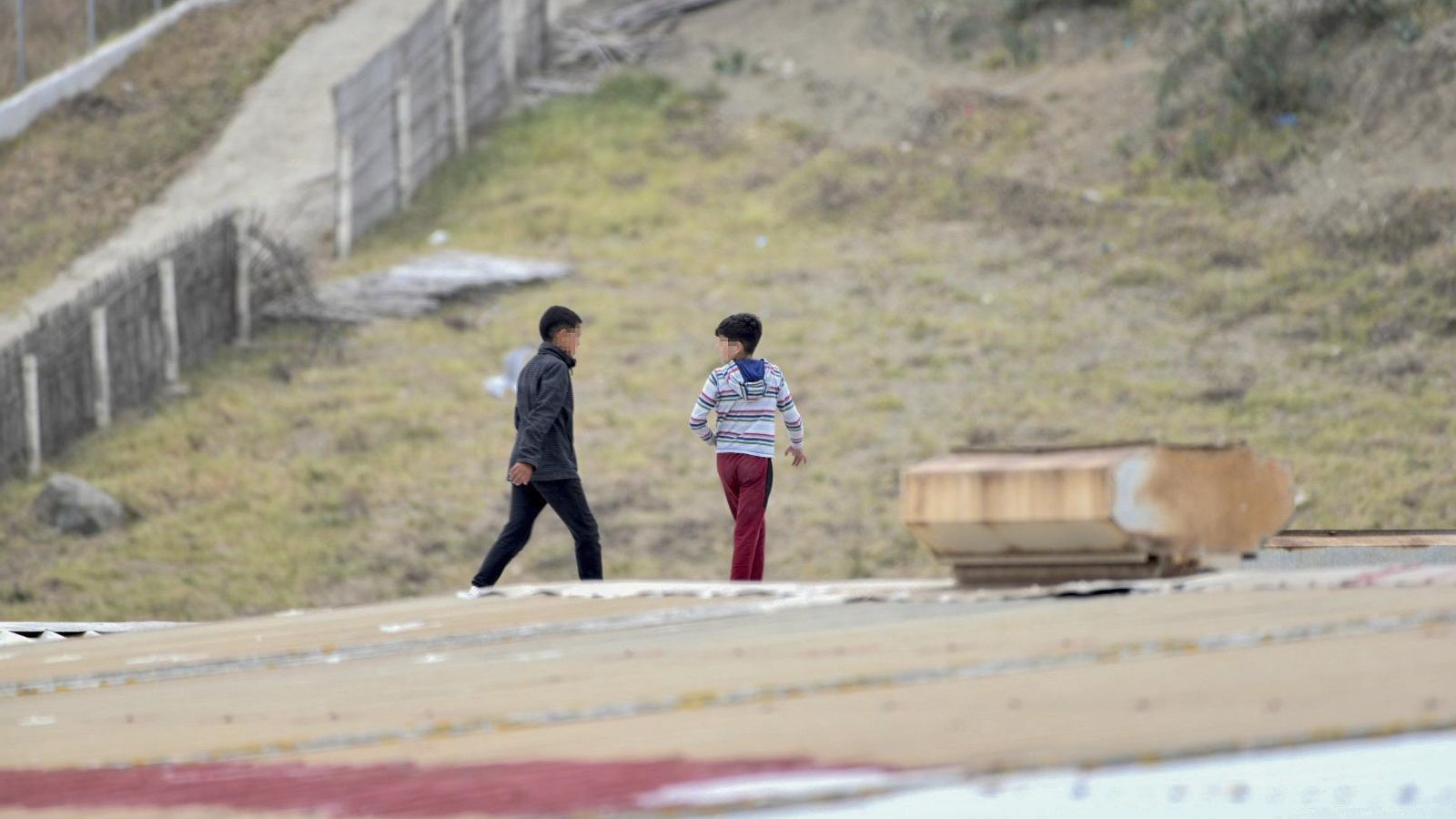 Diversos xiquets caminen per una teulada en tractar d'escapar de la nau de primer acolliment del polígon del Tarajal, a Ceuta.