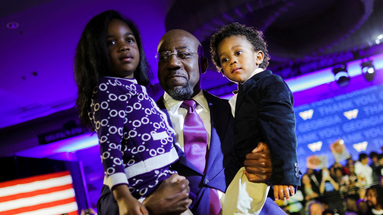 El reverend Raphael Warnock, candidat demòcrata, sosté els seus fills després de conéixer els resultats electorals