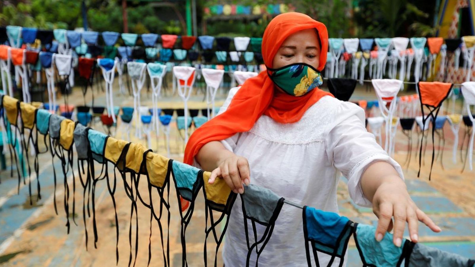 Una dona estén mascaretes de tela abans de distribuir-les de forma gratuïta pel barri, aquest dijous a Jakarta, Indonèsia
