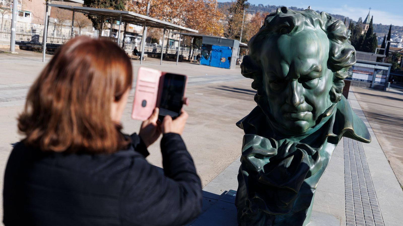 Una dona pren una fotografia a una de les estatuetes gegantesques situada a un passeig de Granada, seu de la última gala dels Goya