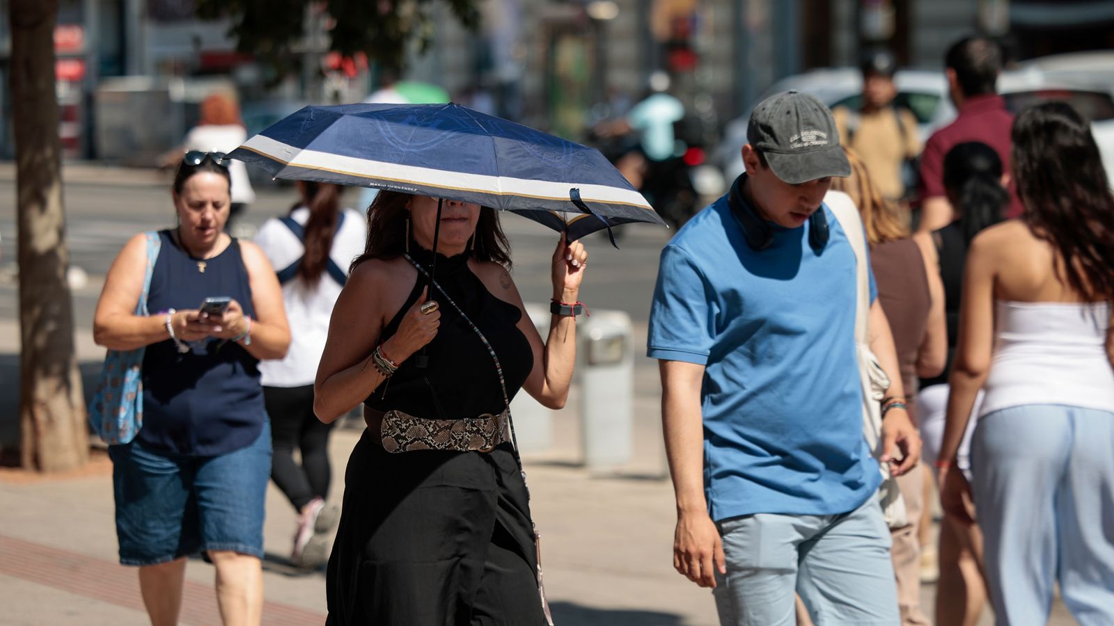 Una dona es protegix de la calor amb un paraigües a València