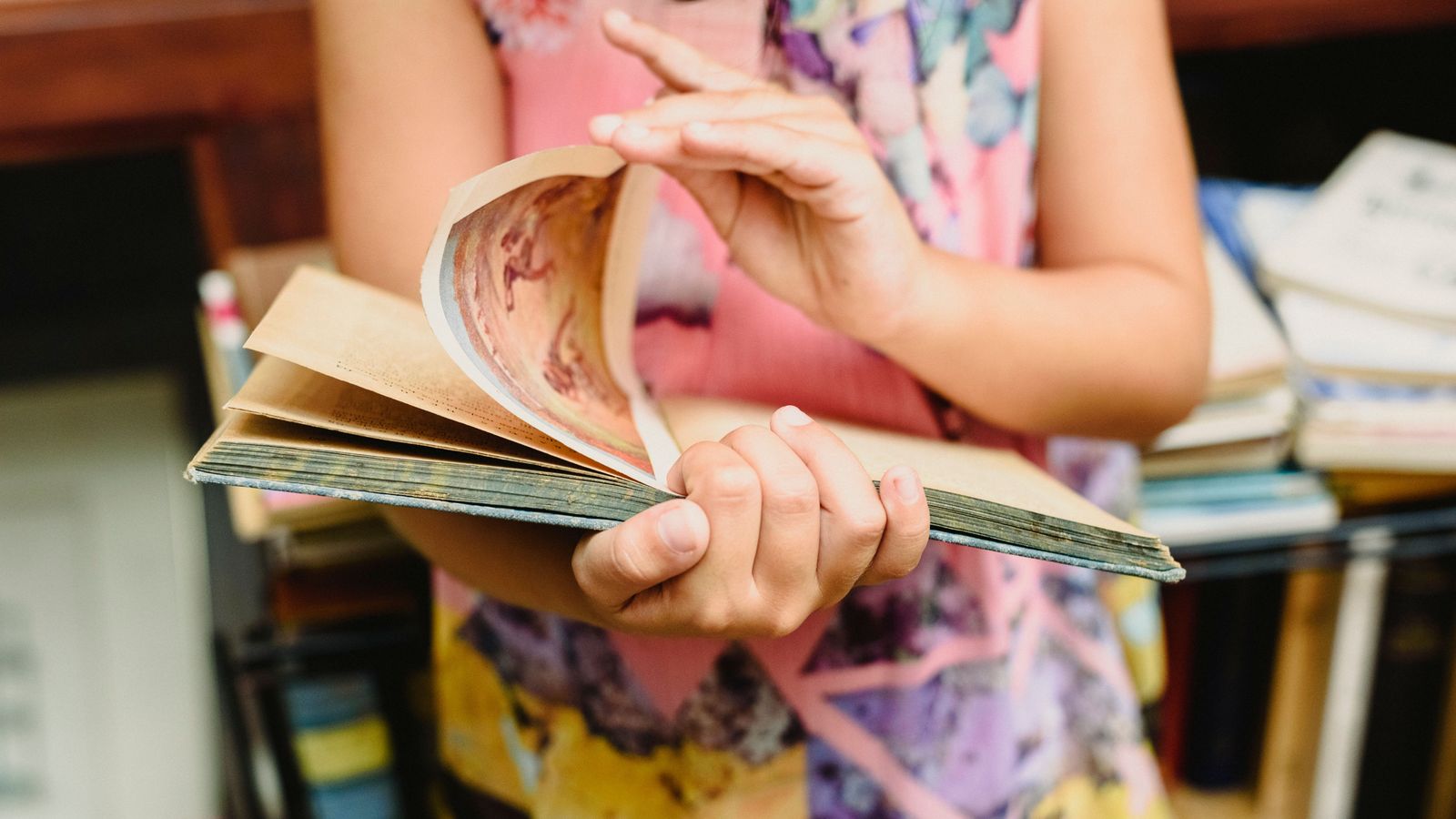 Una dona passa una pàgina d'un llibre en una biblioteca, en una imatge d'arxiu