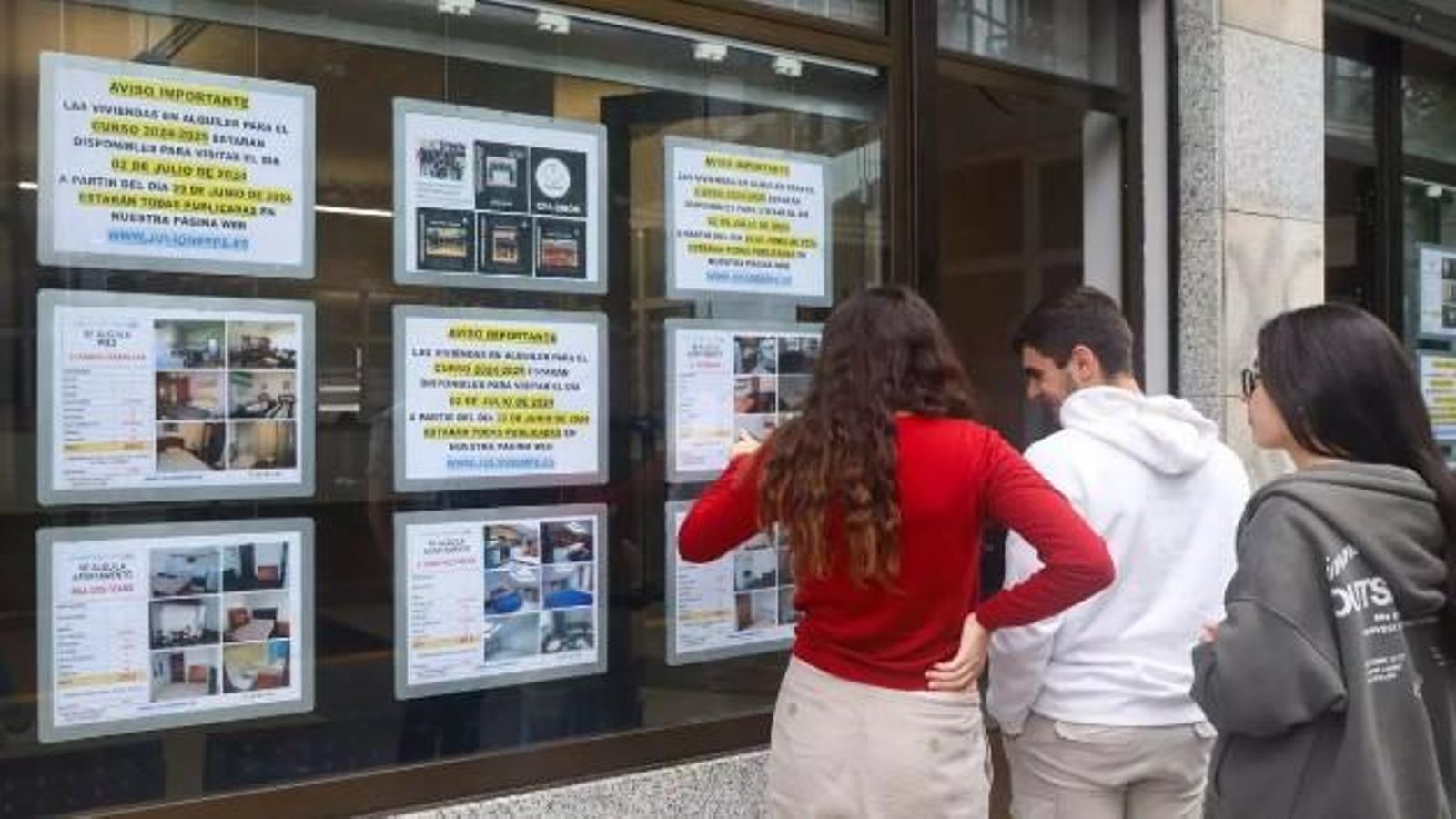 Joves miren anuncis de pisos en lloguer en una immobiliària