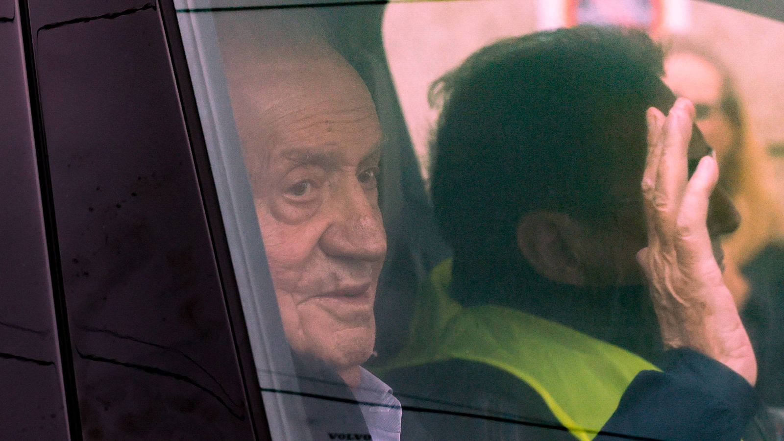 El rei Joan Carles saluda des del vehicle que el va arreplegar a l'aeroport de Vigo, on va arribar en un vol privat