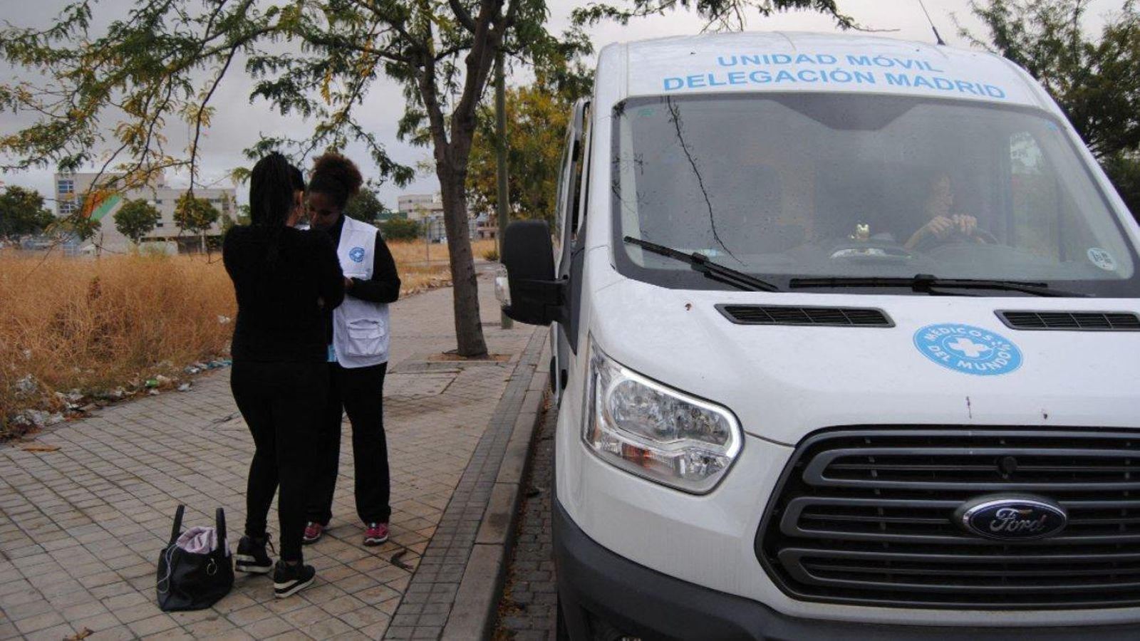 Una tècnica de Metges del Món parla en una dona en una via pública de la comunitat de Madrid