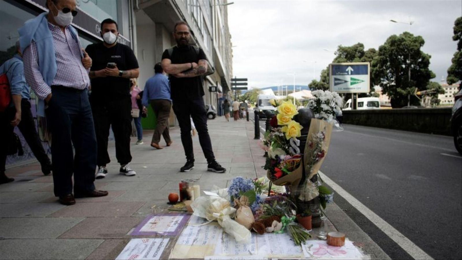 Diversos vianants observen l'altar improvisat, amb flors i missatges, que s'ha creat al punt on van matar Samuel