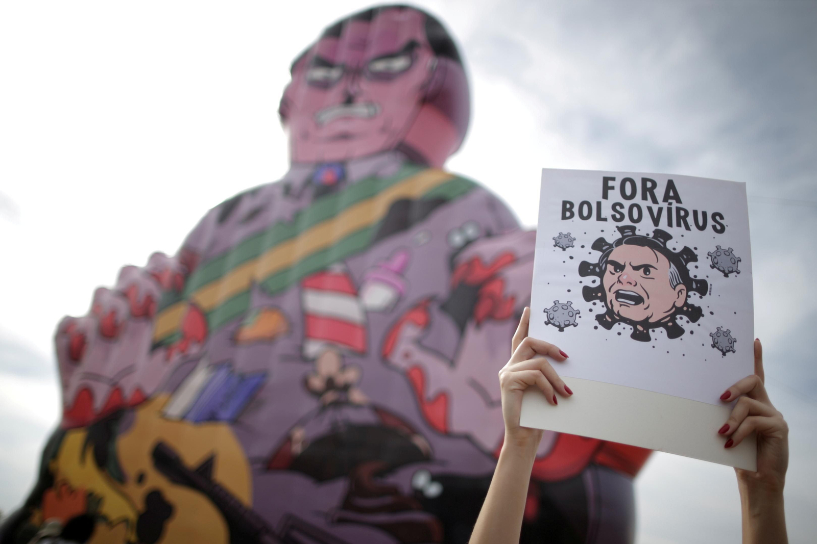Un manifestant mostra un cartell que diu "Fora Bolsovirus" en una manifestació a Brasília