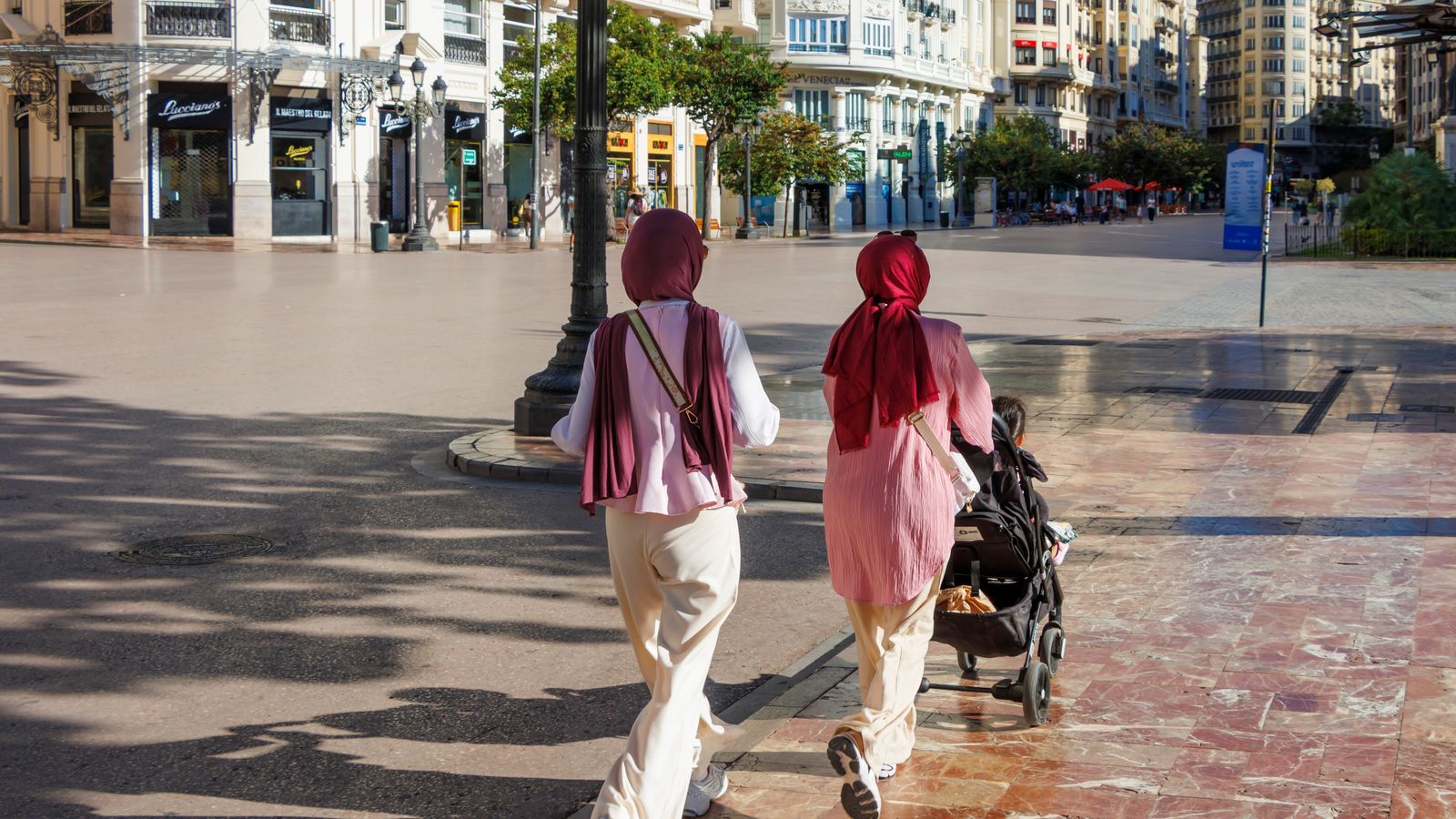 Dos persones passegen per la ciutat de València amb un carret de rodes