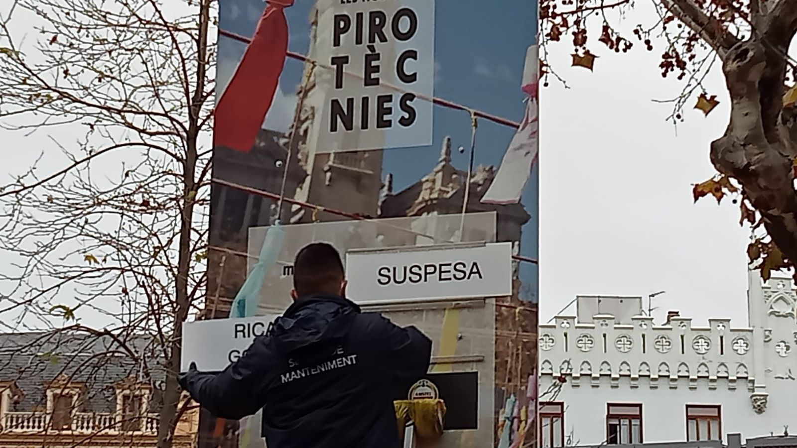 Un treballador municipal penja el cartell que anuncia que la mascletà d’aquest dilluns queda suspesa