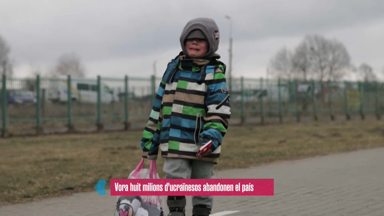 Un xiquet ucraïnes víctima de la guerra camina plorant i tot sol per una carretera, amb la seua motxilla