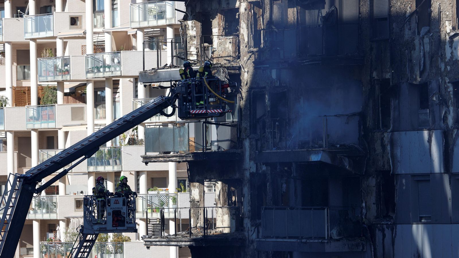 Els bombers treballen amb grues en la façana de l'edifici