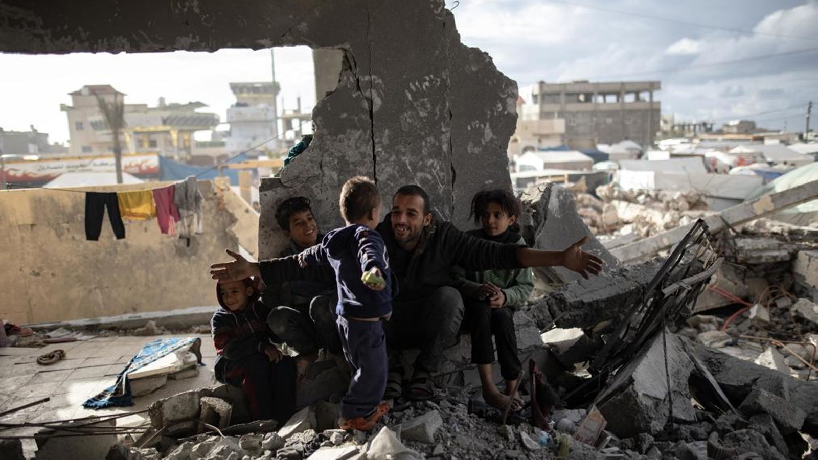 El desplaçat palestí Muhammad Al-Durra, de 41 anys, juga amb els fills entre els enderrocs de la casa destruïda que li dona sostre a Rafah, al sud de la Franja de Gaza