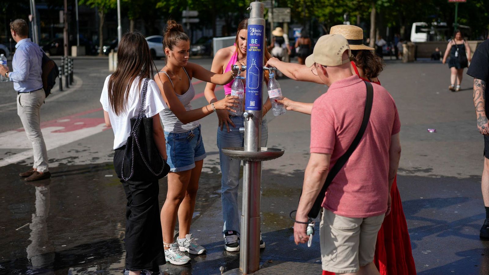Diverses persones omplin botelles d'aigua en una font pública de París, una de les ciutats assotades per l'onada de calor