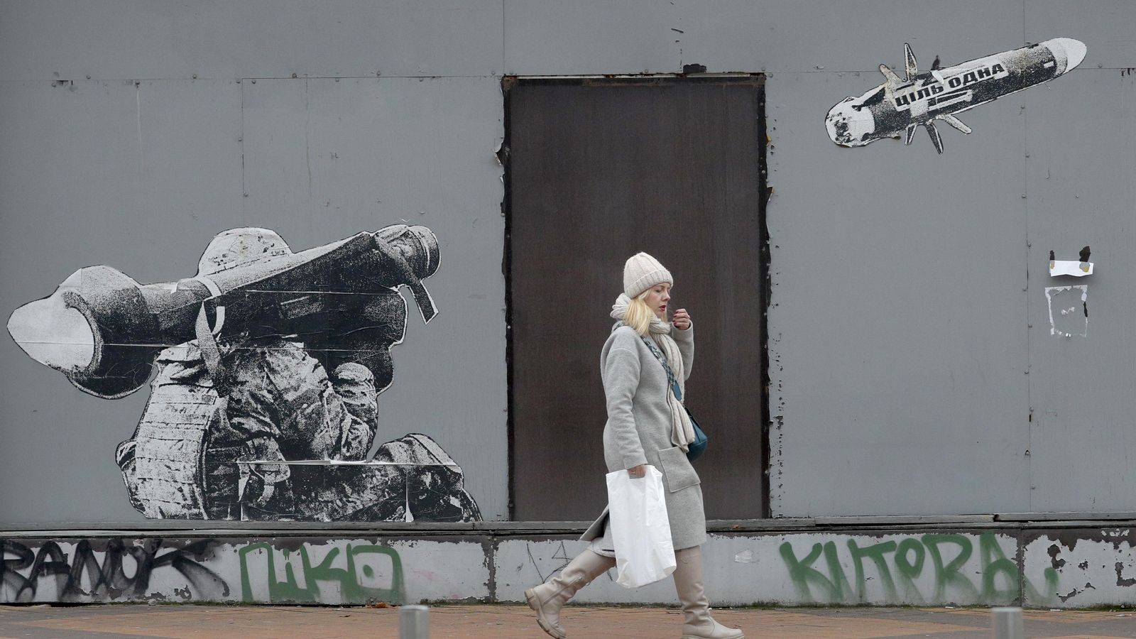 Una dona camina al costat d'un grafiti que mostra a un soldat ucraïnés llançant un míssil que porta escrit el missatge "només un objectiu", a Kíiv