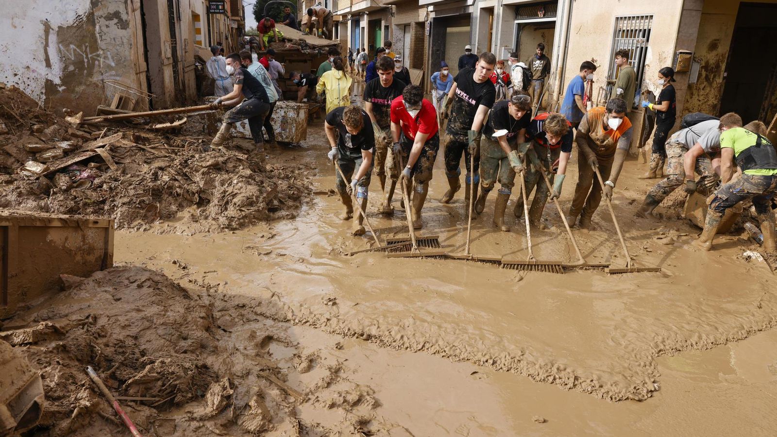 Voluntaris netegen el fang d'un carrer de Massanassa, a l’Horta Sud, este dijous.