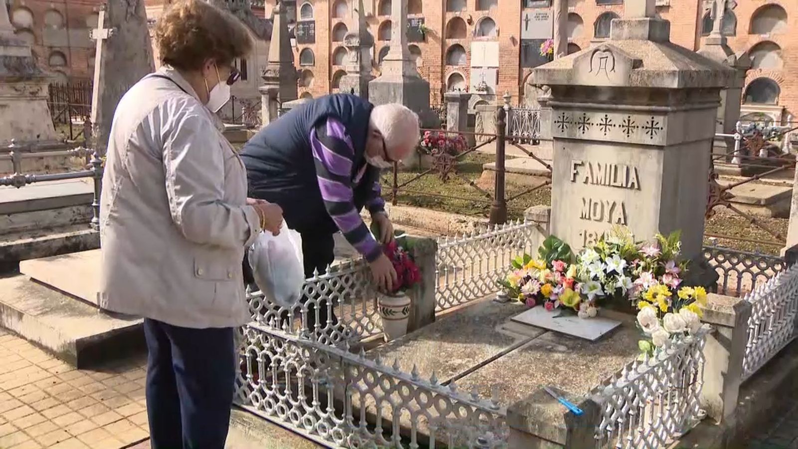 Una parella deposita flors a la tomba familiar, en la víspera de Tots Sants
